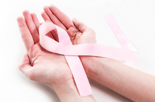 Two hands gently holding a pink ribbon.