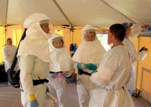 Medical staff wearing biohazard suits inside tent