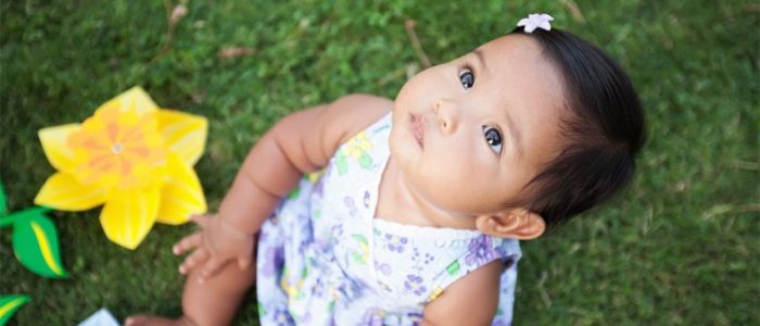 Photo: Toddler looking at the sky while sitting on the grass