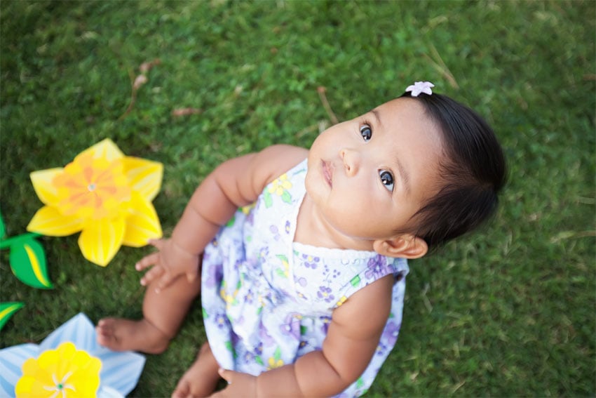 Photo: Toddler looking at the sky while sitting on the grass