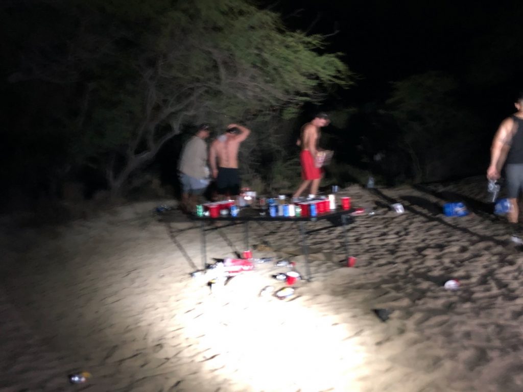four beach goers leaving a table with red cups at night