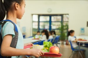 A child walking with lunch tray. 