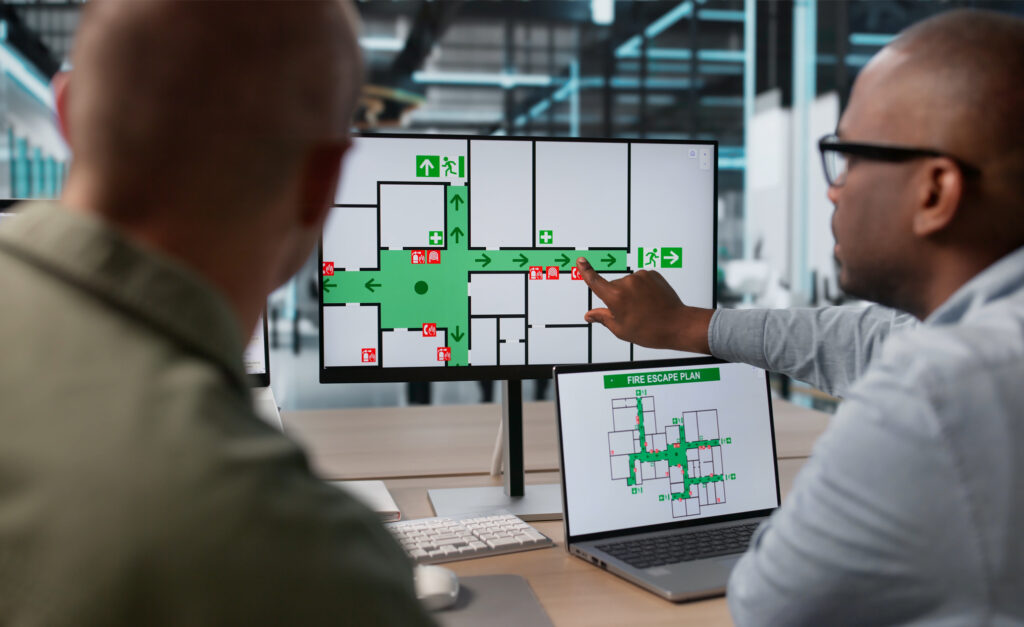 Two persons in front of a computer screen showing a diagram.