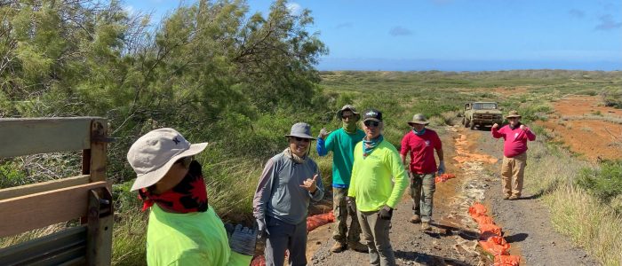 Six people in workwear, in front of a truck, on the mostly barren island of Kaho'olawe