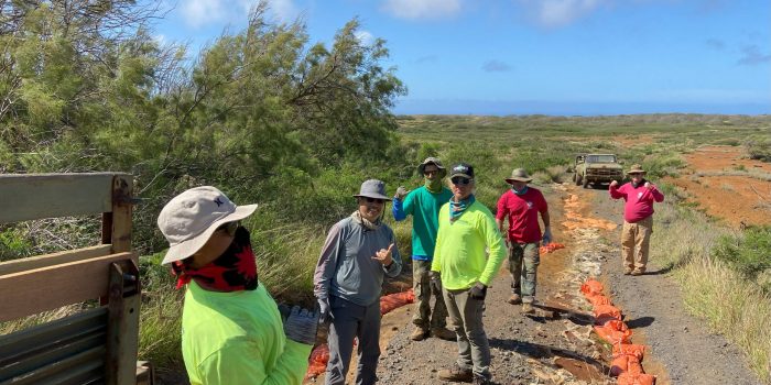 Six people in workwear, in front of a truck, on the mostly barren island of Kaho'olawe