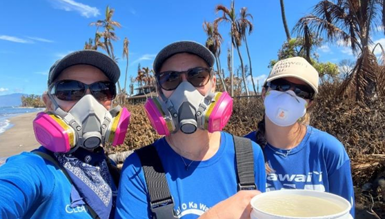 three people wearing personal protective equipment pose with a water sampling bucket